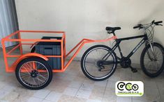 an orange bike with a cart attached to it next to a black and white bicycle