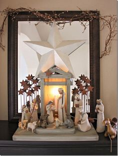 a nativity scene is displayed in front of a mirror with candles and stars on it