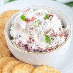 a white plate topped with crackers and a bowl filled with coleslaw salad