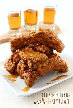 chicken fried ribs with whiskey glaze on a white plate next to three shot glasses