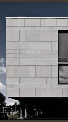 the side of a white building with windows on it's sides and sky in the background