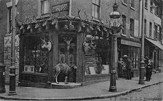 an old black and white photo of a store front with deer heads on it's display