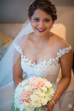 a woman in a wedding dress is holding a bridal bouquet and smiling at the camera