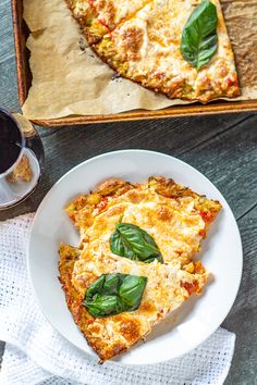 a slice of pizza on a white plate next to a glass of wine and a napkin