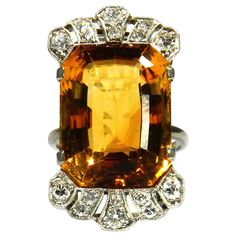 Art Deco 18.7 Carat Citrine Diamond Cocktail Ring in 18K White Gold, circa 1930 Elegant cocktail ring with a lattice-shaped openwork ring head, set with a magnificent cognac-colored 18.7 carat citrine, crowned by diamonds totaling 0.5 carat 18K white gold 1 citrine approx. 18.7 ct carat in emerald cut, 18.53 x 14.25 mm 16 brilliant-cut diamonds, total approx. 0.50 ct, G-H / Si-P Ring head size 29.84 x 17.03 mm Ring size 53 Weight 10.39 g stamped 750 very good condition Supplied with an Independe Vintage Octagon Ring With Center Stone, Vintage Rings With Octagon Center Stone, Art Deco Topaz Ring With Center Stone, Art Deco Octagon Ring For Formal Occasions, Formal Art Deco Octagon Ring, Art Deco Yellow Gold Topaz Ring, Vintage Yellow Rings With Prong Setting, Art Deco Citrine Topaz Ring For Formal Occasions, Vintage Octagon Gemstone Ring