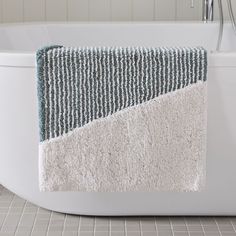 a white bath tub sitting next to a bathroom sink under a faucet with a towel hanging on it