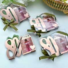 three pink and green tags with bows on them sitting next to each other in front of flowers