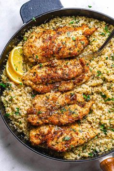 chicken and rice in a skillet with lemon wedges on the side for garnish