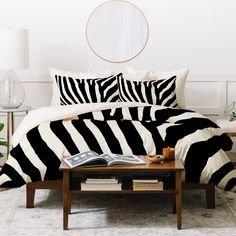 a zebra print comforter set on a bed in a room with a round mirror