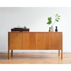 an old record player sits on top of a wooden cabinet with two vases next to it