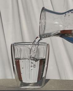 a glass filled with water being poured into it