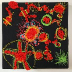 a black square with red and green flowers on it, surrounded by other small objects