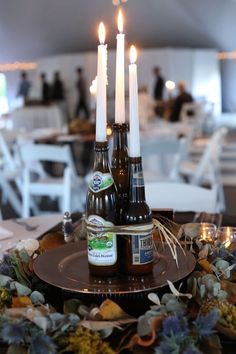 two beer bottles sitting on top of a plate with candles in the middle of it