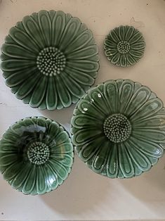 three green plates sitting on top of a white table next to each other and one has a flower in the middle