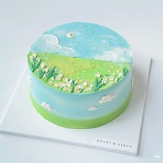 a blue and green cake sitting on top of a white table next to a book