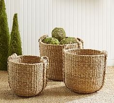 three woven baskets sitting next to each other on top of a carpeted floor with trees in the background