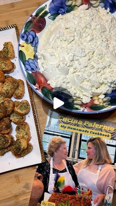 two women standing in front of a plate of food on a table next to magazines