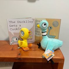 two stuffed animals sitting on top of a wooden table next to a bookshelf