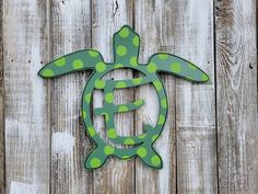 a green and white turtle with polka dots on it's head is mounted to the side of a wooden fence