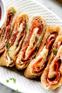 several sandwiches on a white plate with sauce and parsley in the middle, ready to be eaten