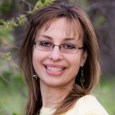 a woman with glasses smiling for the camera