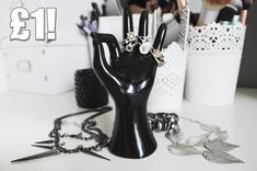 a black hand is holding several rings on it's fingers with scissors and other accessories nearby