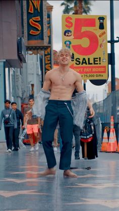 a shirtless man walking down the street in front of a sign that says 5 sale