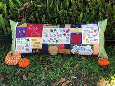 a patchwork pillow is sitting on the ground with two pumpkins in front of it