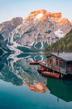 two boats are docked in front of a mountain lake