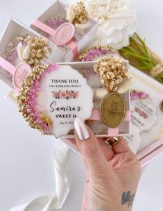 a person holding up a small box with flowers on it and a medal in the middle