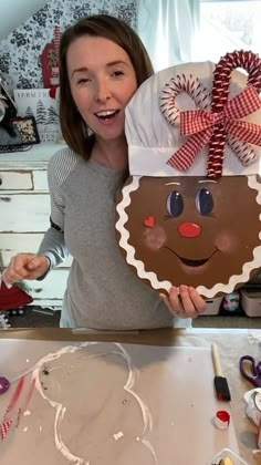 a woman holding up a gingerbread cookie