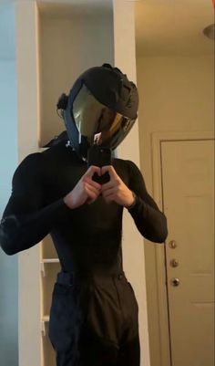 a man in a black suit and helmet taking a selfie