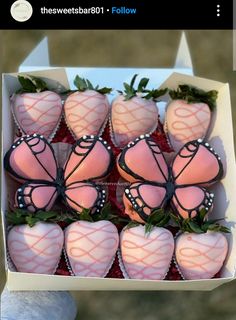 chocolate covered strawberries are in a box with pink frosting and green leaves on them