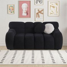 a black couch sitting on top of a hard wood floor next to a white rug