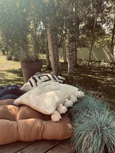 a blanket and pillows are sitting on a wooden table in the grass near some trees