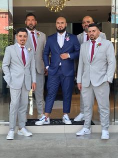 four men in suits and ties posing for a photo outside the entrance of a building