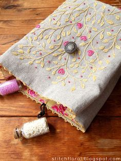 a small bag sitting on top of a wooden floor next to two spools of thread