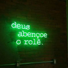 a neon sign that reads deus abenge o role on a brick wall