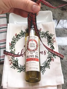 a bottle of extra virgin olive oil sitting on top of a white plate with a red and green ribbon