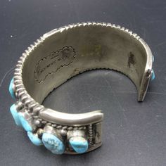 "VINTAGE NAVAJO BRACELET DESCRIPTION: This impressive cuff features 21 specimens of blue Arizona turquoise.. The gemstones are secure in smooth bezel, on a foundation of heavy gauge vintage sterling silver. Plump applied raindrops punctuate the turquoise cabochons and chisel stamped designs frame the edges. This fine bracelet will be a cherished addition to your collection of fine vintage Native American jewelry. MEASUREMENTS: Interior of the cuff measures 5 7/8\" with an additional 1 1/4\" non- Vintage Cuff Bracelets For Collectors, Handmade Vintage Cuff Bangle, Vintage Cuff Bracelets Collectible, Vintage Blue Cuff Jewelry, Collectible Vintage Cuff Bracelet, Vintage Blue Cuff Bracelet, Vintage Blue Bangle Bracelets, Adjustable Vintage Rectangular Cuff Bracelet, Vintage Stamped Blue Jewelry