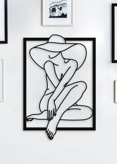 a black and white drawing of a woman sitting in front of pictures on the wall