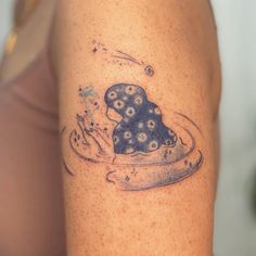 a woman's arm with a tattoo on it that has an image of a hat