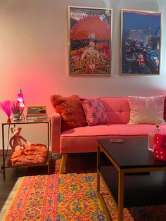 a living room with pink couches and colorful rugs in front of posters on the wall