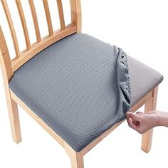 a person is holding the seat cushion on a chair