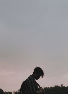 a man standing on top of a lush green field next to a kite flying in the sky