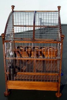 a bird cage with several birds in it on top of a wooden stand next to a wall