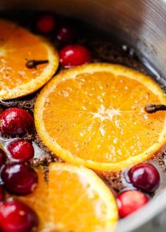 oranges and cranberries are being cooked in a pot