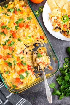 an enchilada casserole in a glass dish with a serving spoon