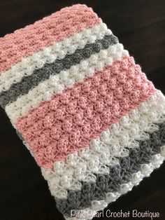 a crocheted dishcloth is sitting on a wooden table with a black and white stripe