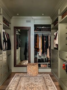 a walk in closet with an area rug on the floor and clothes hanging on shelves